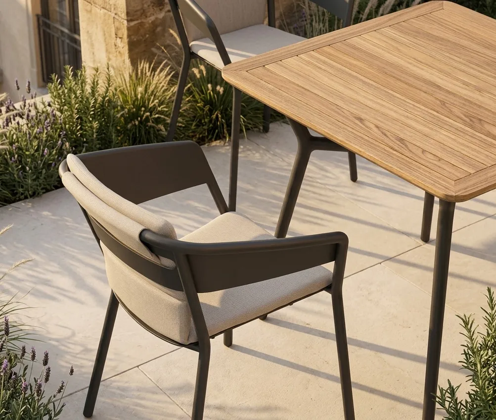 Detailansicht eines ALTEA Armlehnstuhls mit Sitz- und Rückenkissen an einem 90x90 Tisch mit Teakplatte auf einem modernen Balkon